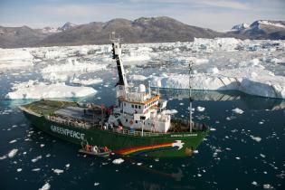 Das Greenpeace Schiff Arctic Sunrise, zwischen Treibeis und Eisbergen, vor dem Helheim-Gletscher im Süd-Osten von Grönland. Die Arctic Sunrise Crew untersucht zusammen mit Wissenschaftler:innen des Woods Hole Oceanographic Institute (USA) die Auswirkungen des Klimawandels auf die Arktis (2009).