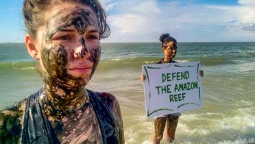 Ölbeschmutzte Aktivisten in Brasilien mit Banner