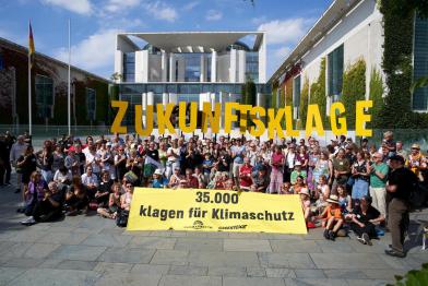 Menschen demonstrieren vor dem Bundestag für die Zukunftsklage, auf dem Banner: 35.000 klagen für den Klimaschutz