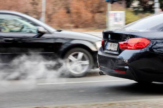 Zwei Autos auf der Straße, aus dem Auspuff quellen Abgase