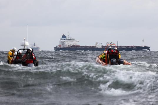 zwei Schlauchboote mit Aktivist:innen auf der Ostsee, im Hintergrund das Schiff