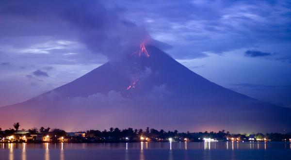 2006: Der philippinische Vulkan Mayon bricht aus. Rauch und Asche gehen über der Stadt Legazpi nieder.